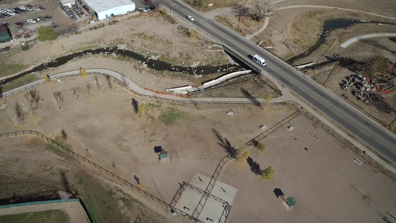 Aerial view of a road crossing dry open land beside a drainage channel.