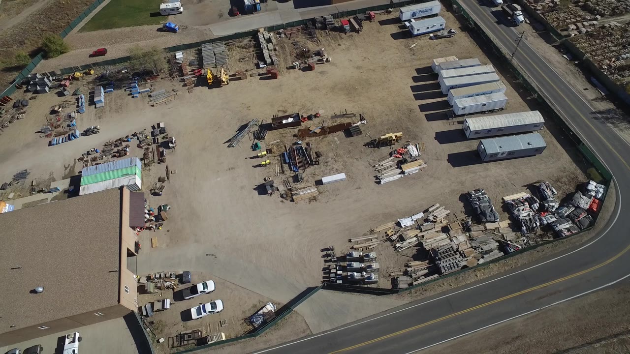 Construction storage yard seen from above with road and equipment piles.