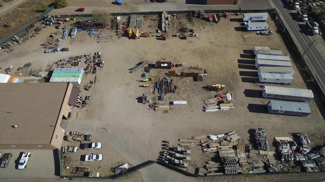 Overhead view of an industrial storage yard with trailers, scrap piles, and warehouse buildings.