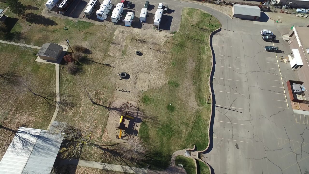 Aerial view of RVs, grass, roads, and a warehouse edge.