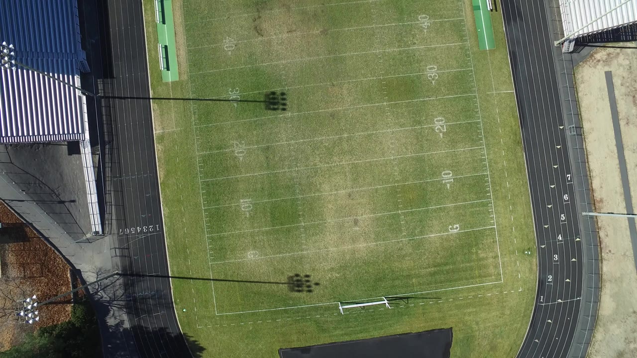 Overhead frame of a Westminster, Colorado football field with yard markings, a black running track, bleachers at the left edge, and no visible people.
