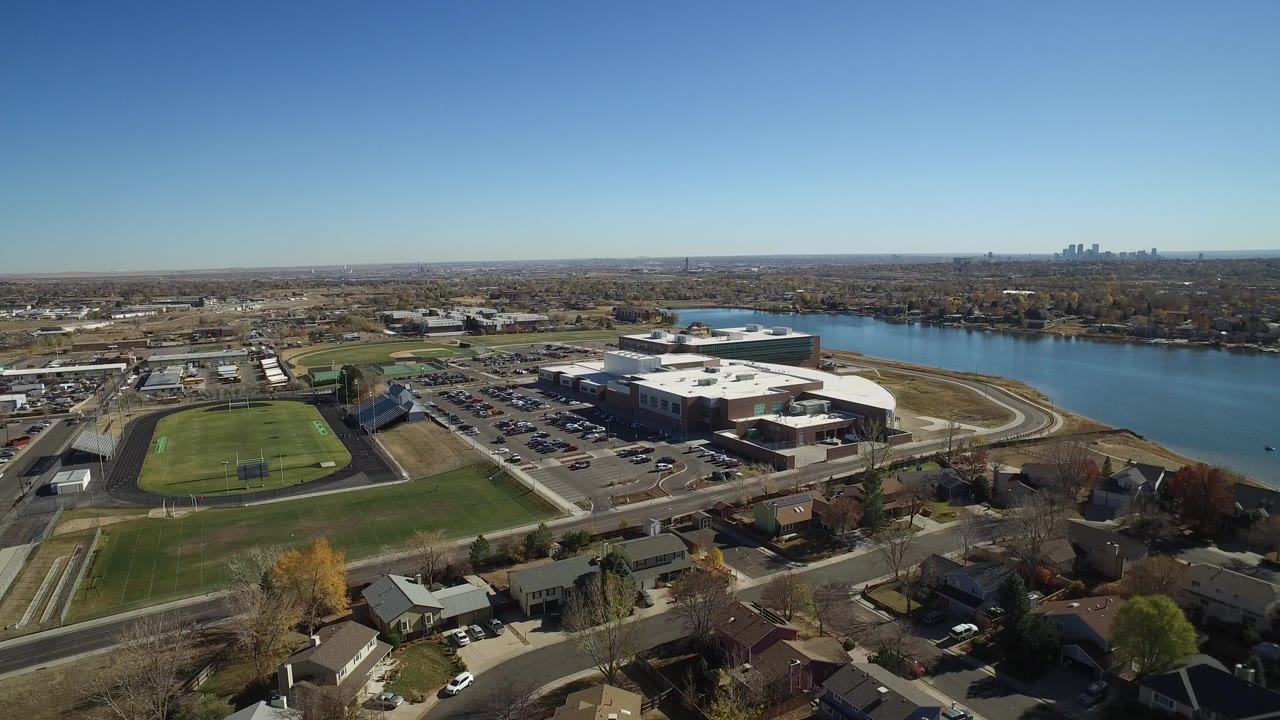 Aerial view of a suburban area beside a lake with athletic fields and large buildings.