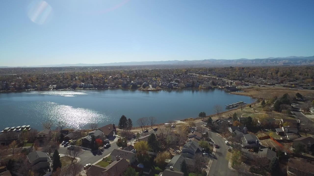 Aerial view of lake, shoreline houses, and distant mountains