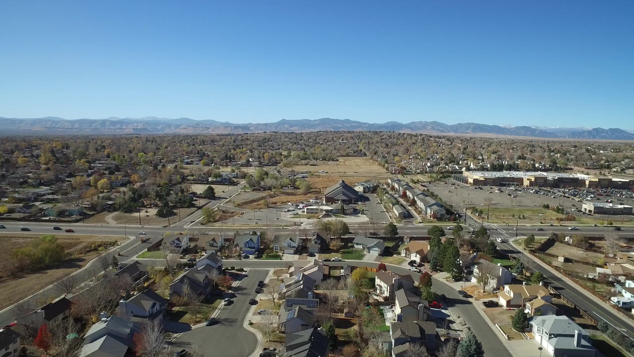 Aerial view of a suburban neighborhood with a cul-de-sac, main road, and distant mountains.