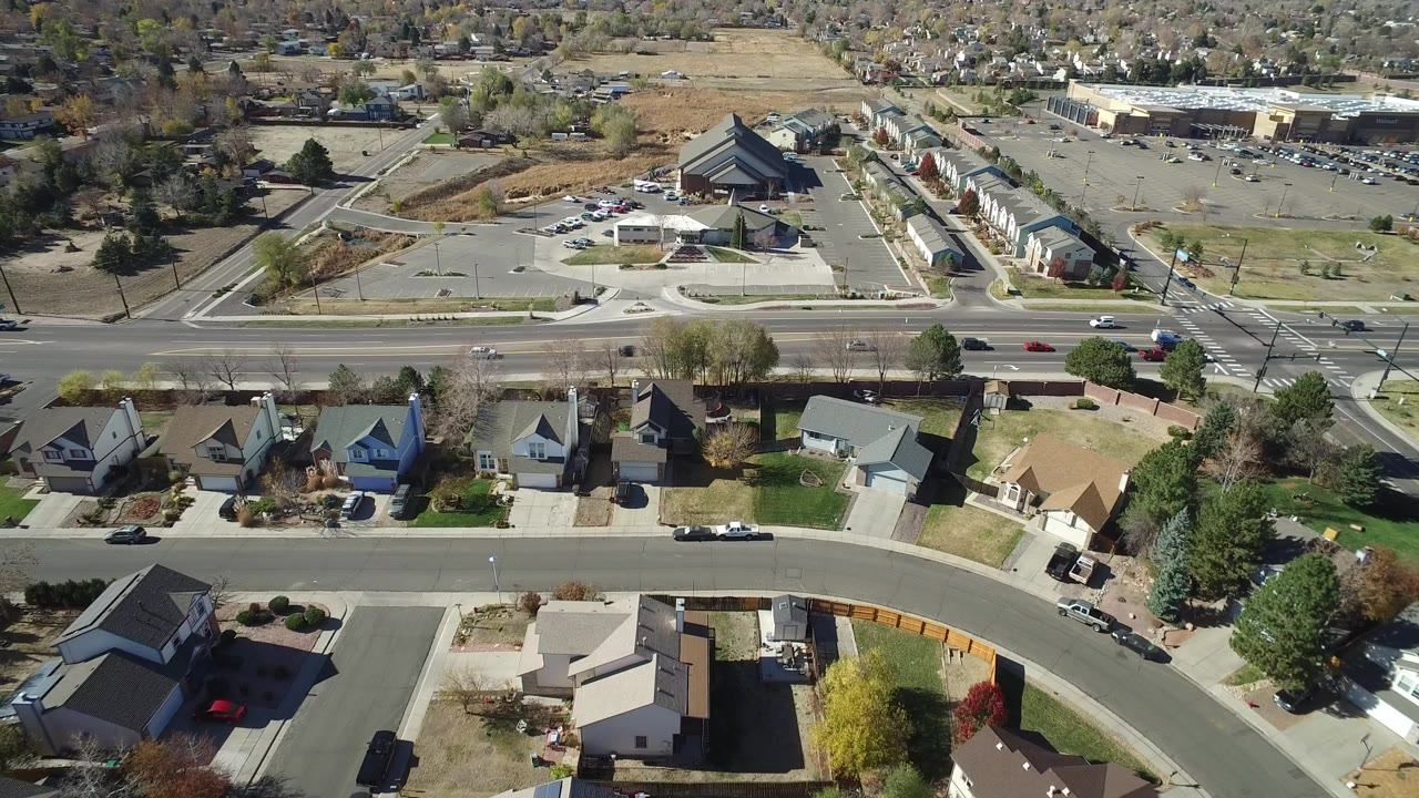 Aerial view of homes, a highway, parking lots, and commercial buildings.