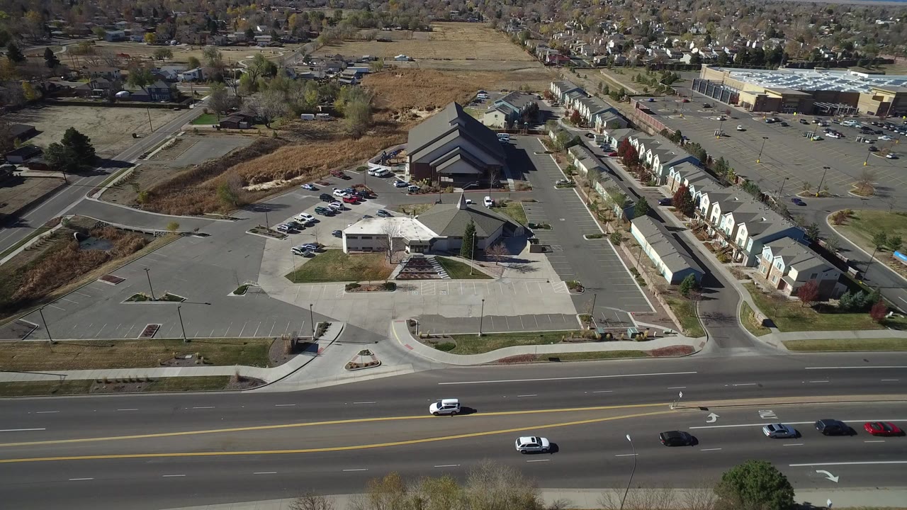 Aerial view of a broad road, parking lots, buildings, and attached homes