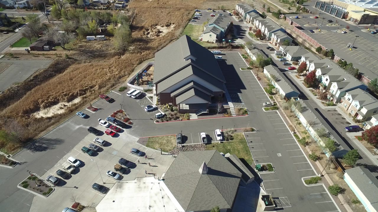 Drone-height view of a full parking area near residential buildings.