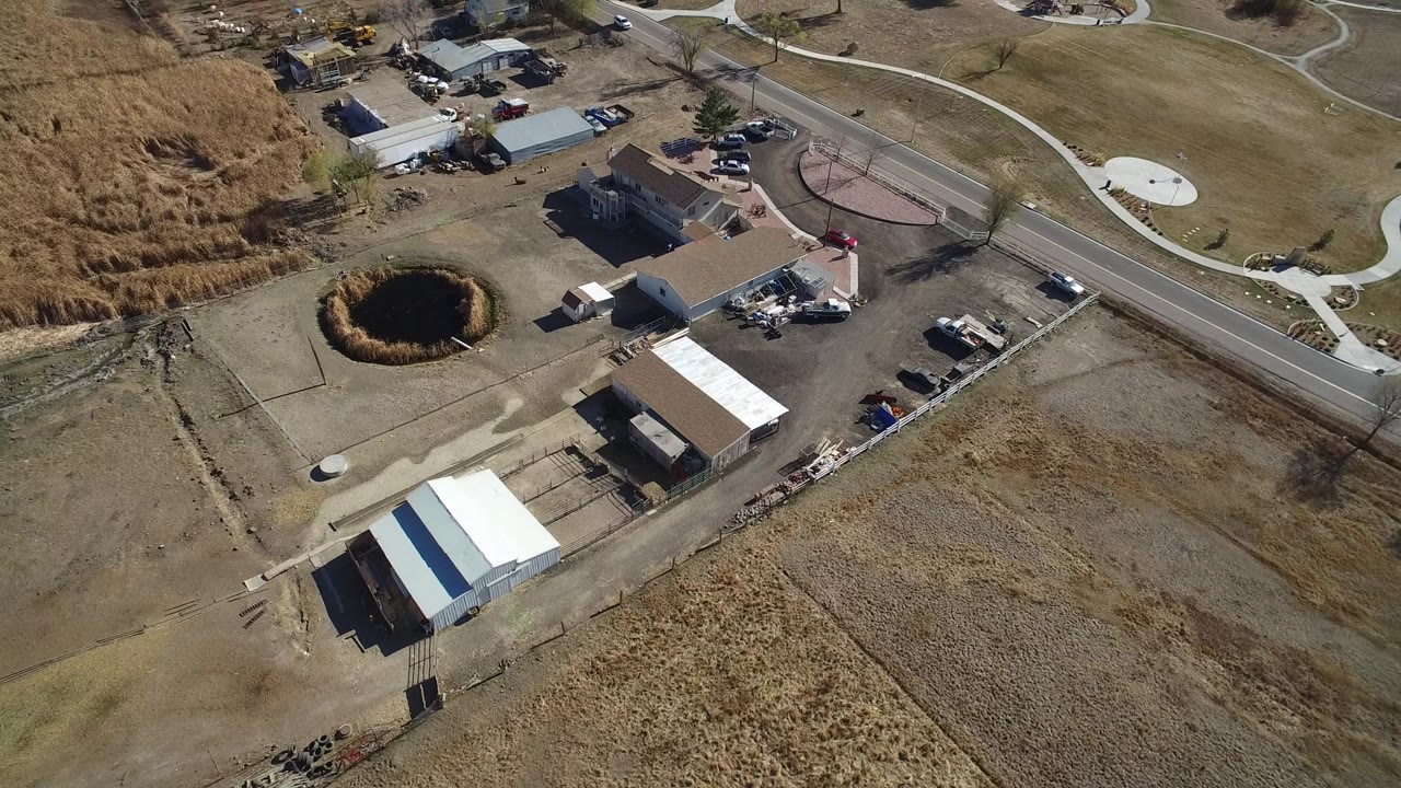 Aerial view of homes, roads, dry fields, and a small pond.