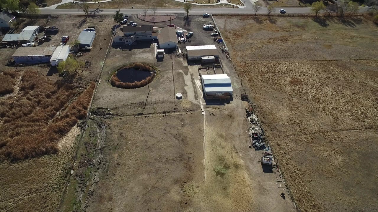 Aerial view of homes, outbuildings, pond, road, and dry fields.
