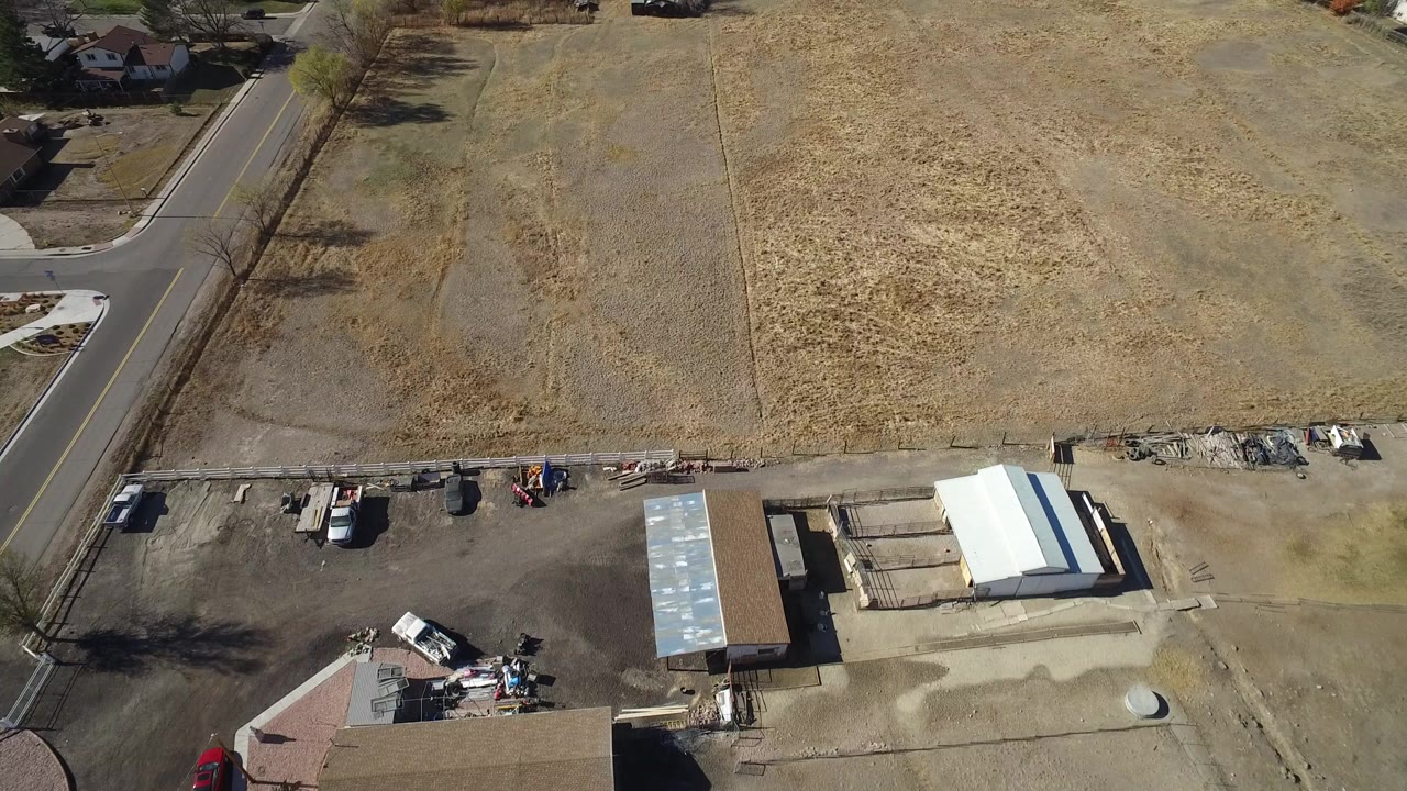 Aerial view of open dry fields beside a paved road and construction yard.