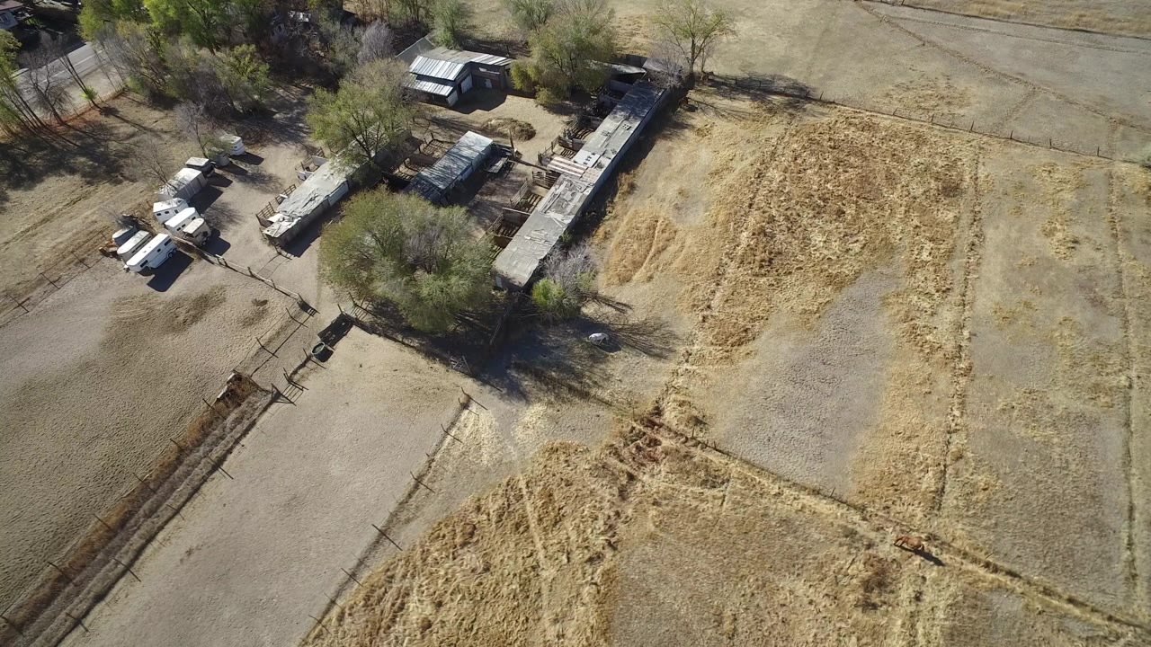 Aerial view of dry marked fields beside trees and small structures.