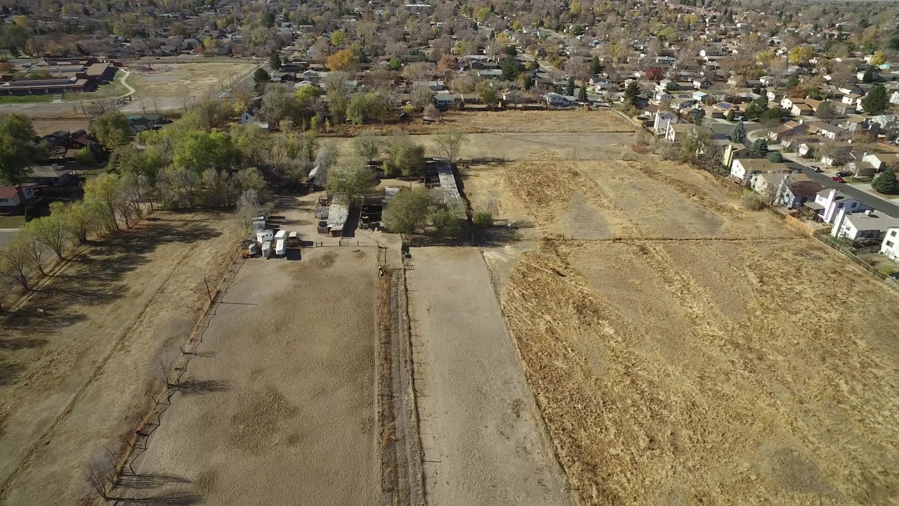 Elevated view of a dirt field beside houses and trees.