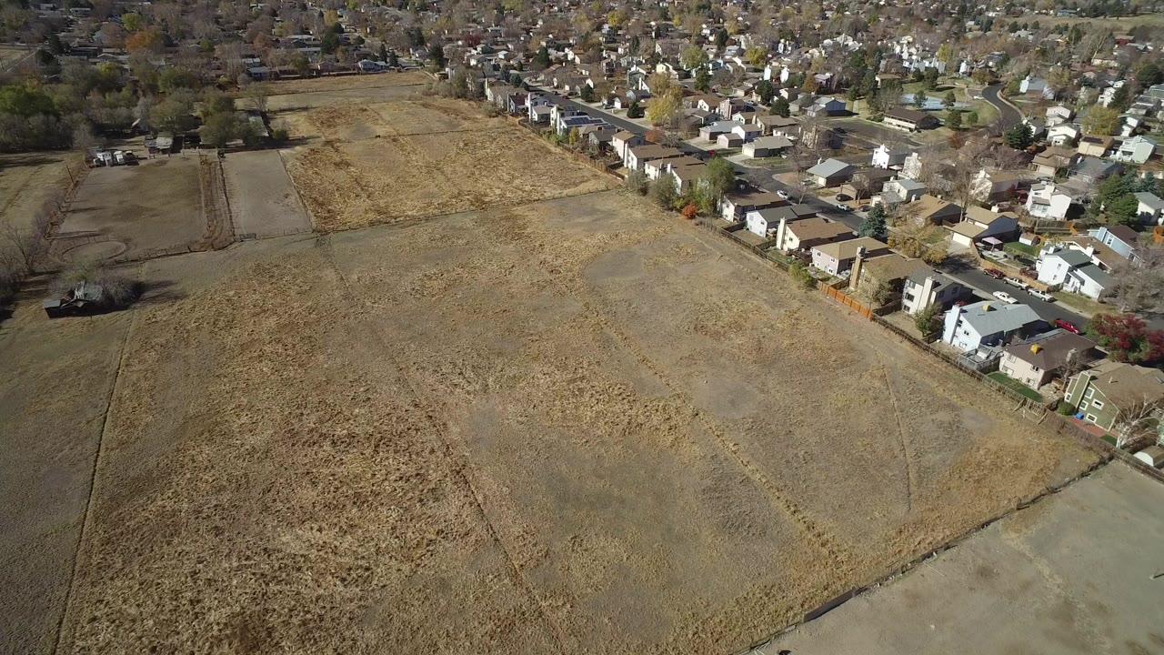 Aerial view of dry fields beside a residential neighborhood.