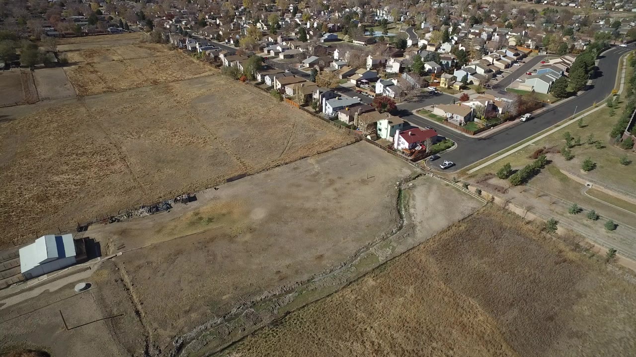 Aerial view of dry fields beside suburban houses and roads