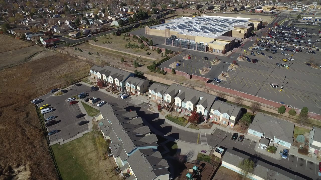 Aerial view of townhomes beside a large parking lot and big retail-style building.