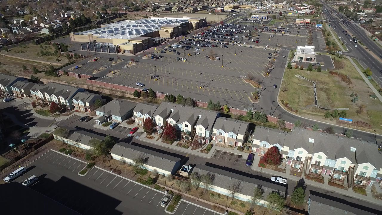 Aerial view of townhomes, a large parking lot, and a public road
