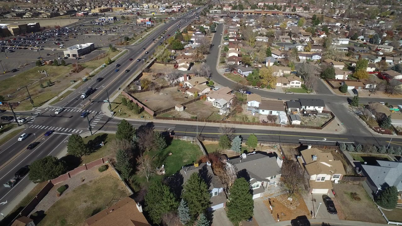 Aerial view of suburban homes beside a multi-lane road and intersection.