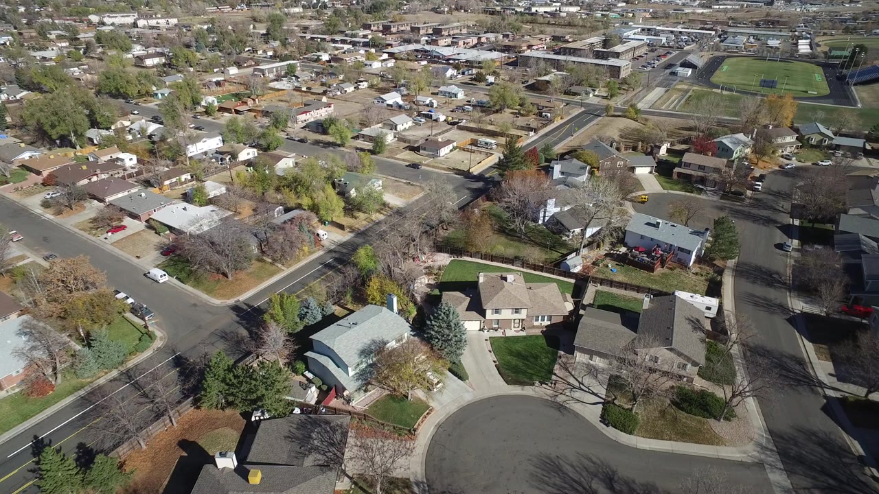 Aerial view over houses, trees, roads, and a school field