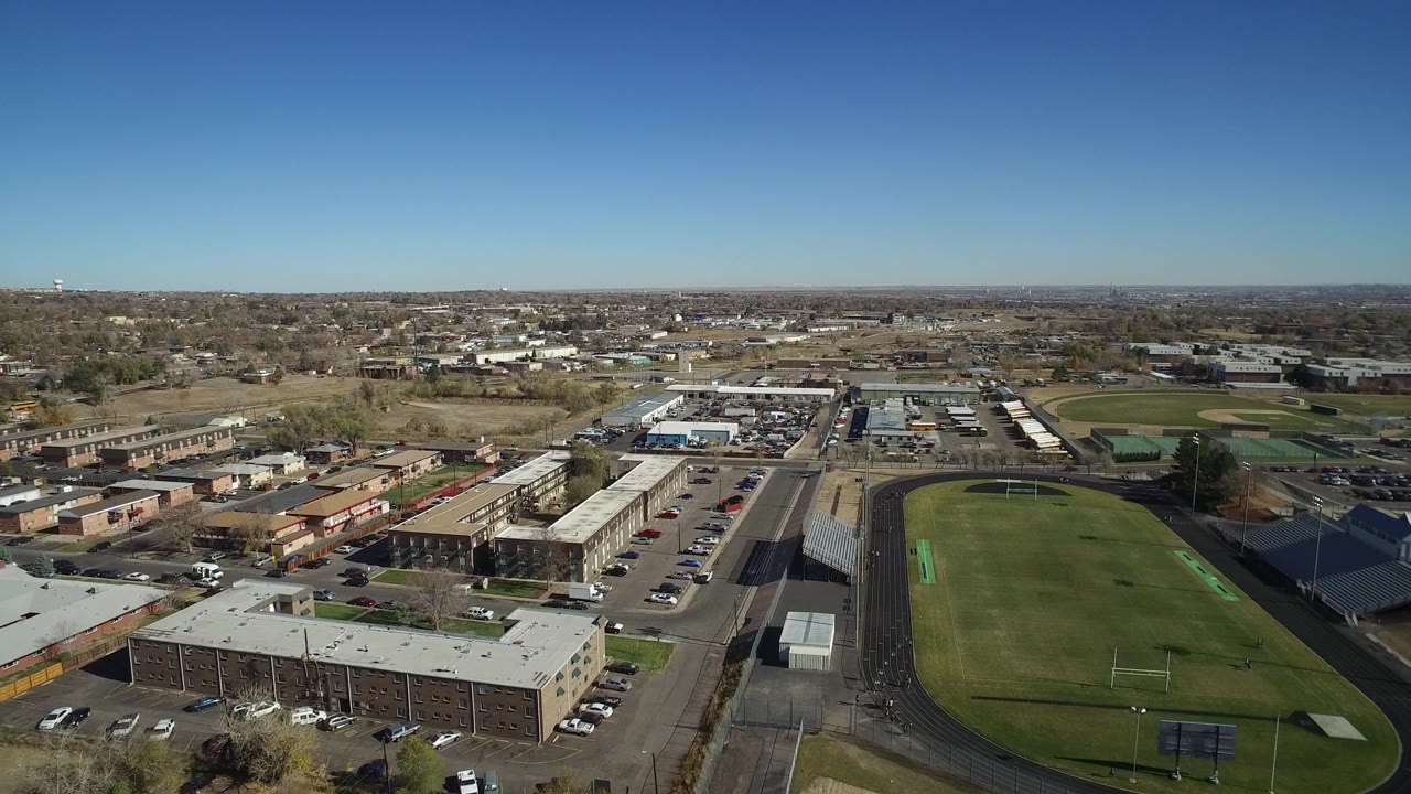 Aerial view of the track and field with bleachers beside roads and suburban buildings.