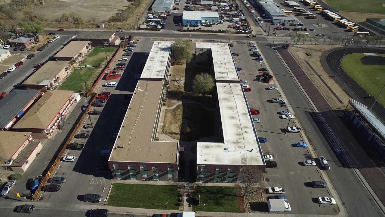 Aerial view of low-rise buildings, parking lots, roads, and athletic fields.
