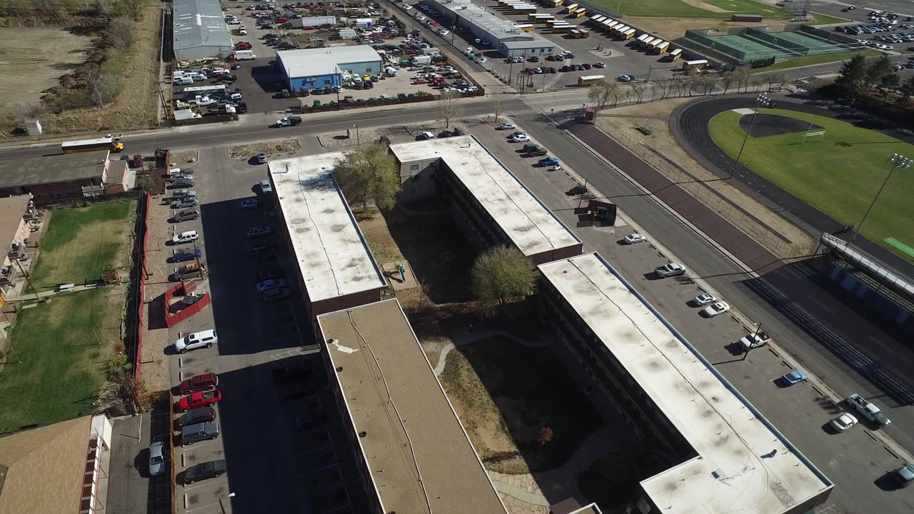 Aerial view of flat-roof buildings beside roads and a sports field.