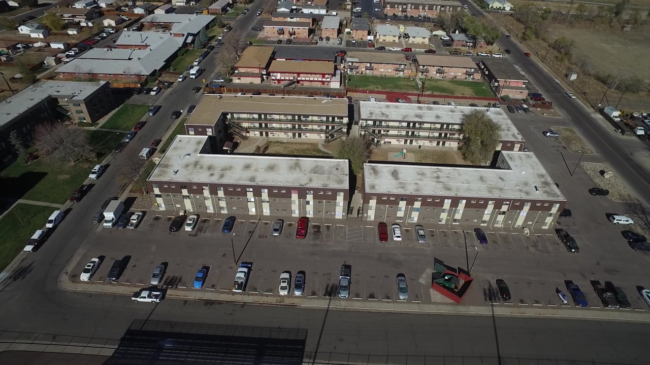 Aerial view of parking rows beside flat-roofed buildings.
