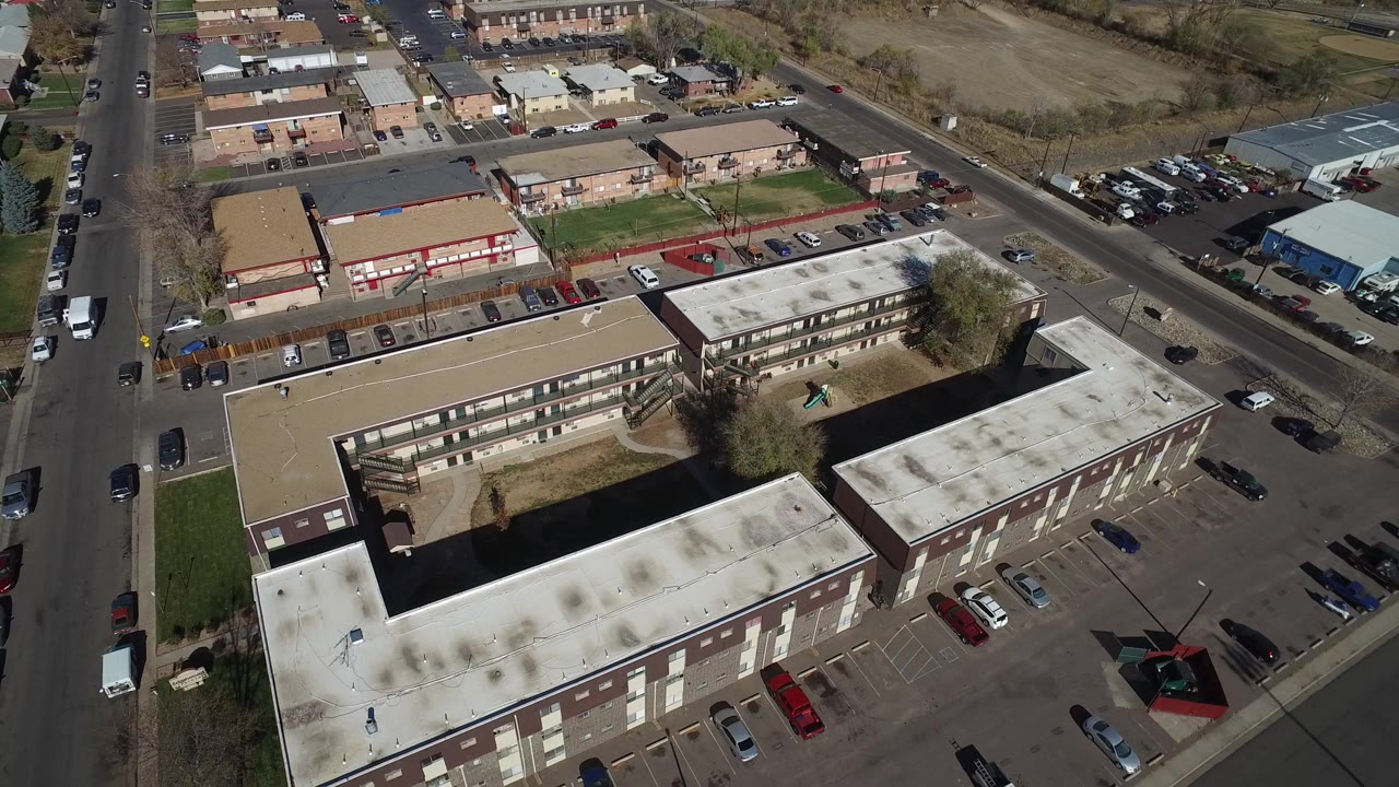 Aerial view of low-rise buildings, parking lots, roads, and nearby houses.