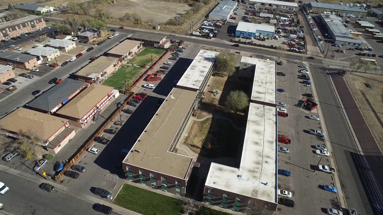 Aerial view of flat-roofed buildings beside parking lots and streets.
