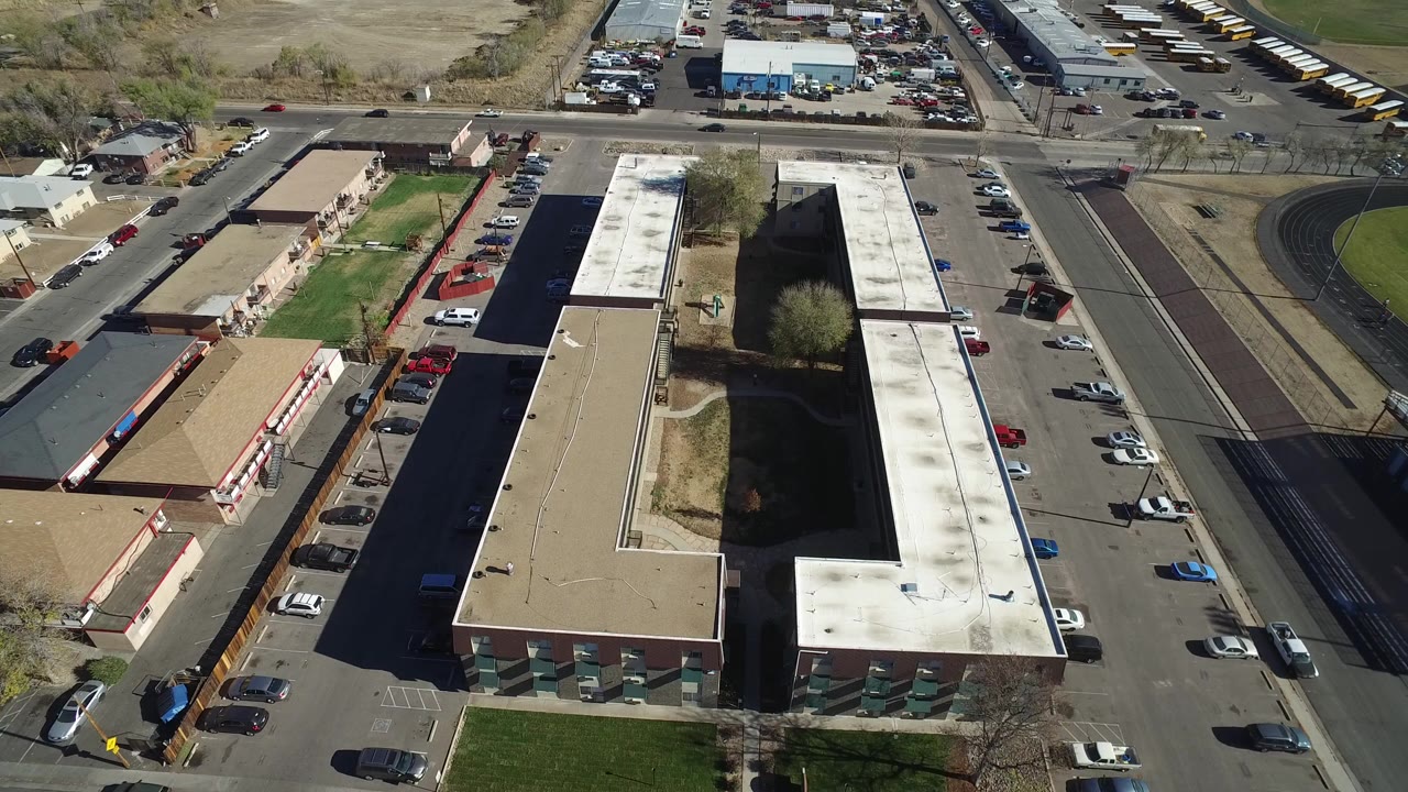 Aerial view of low-rise buildings, parking lots, streets, and cars.
