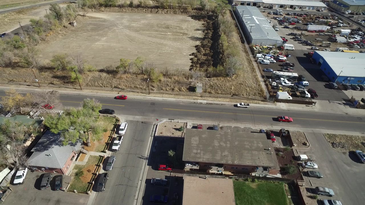 Aerial view of a road beside a vacant lot and parked cars.