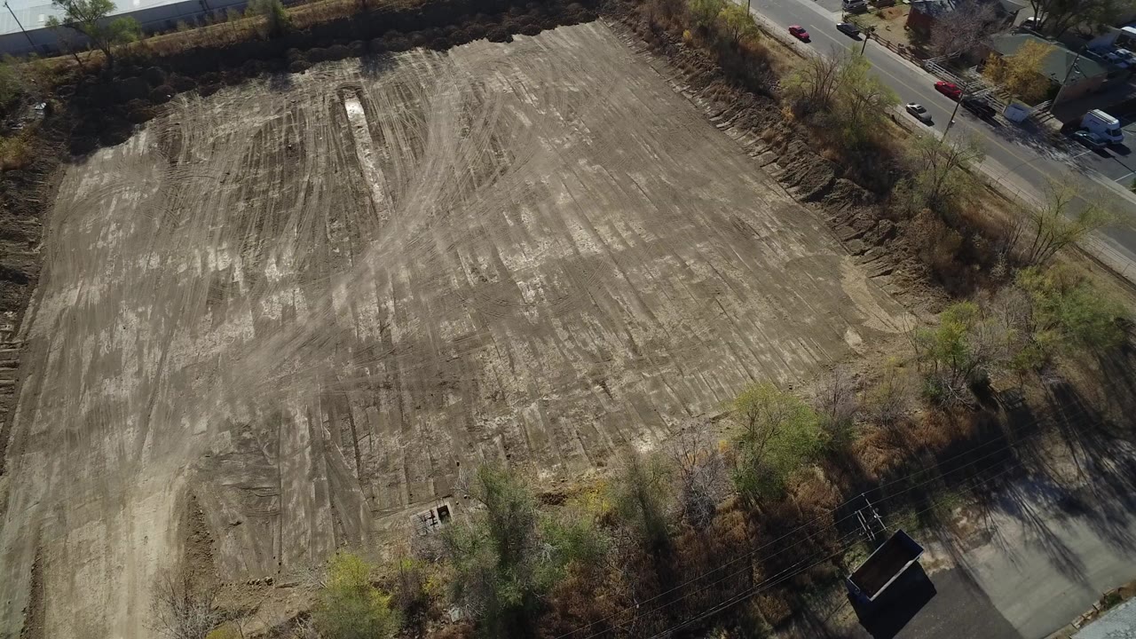 Aerial view of a scraped dirt field beside a road and trees.