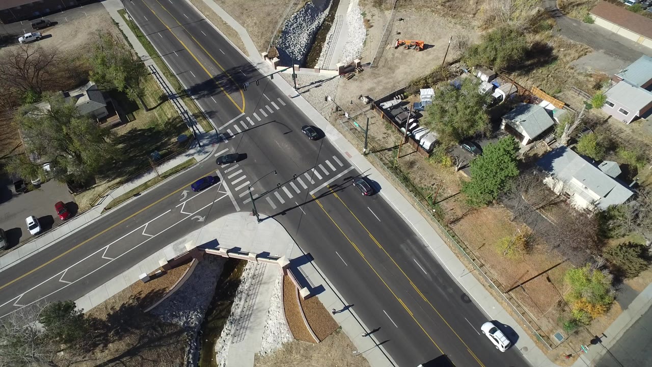 Aerial view of cars on a suburban intersection with sidewalks and homes nearby.