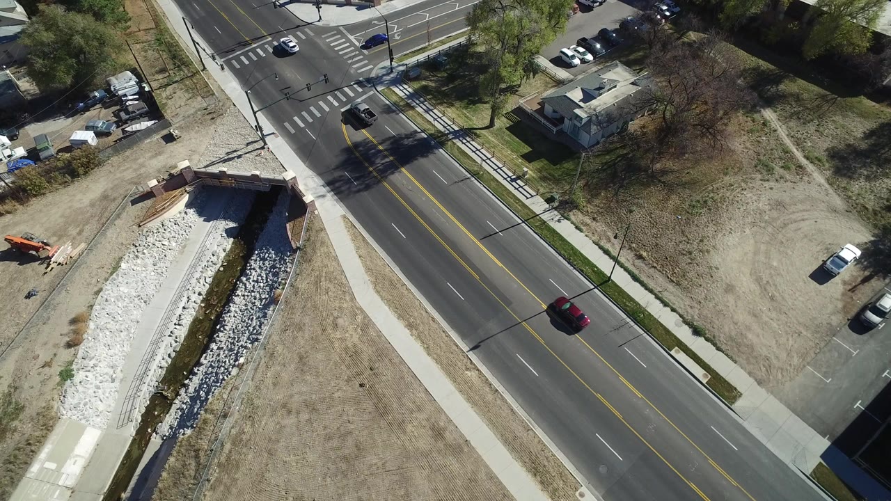 Aerial view of a road, sidewalk, dry grass, and drainage channel.