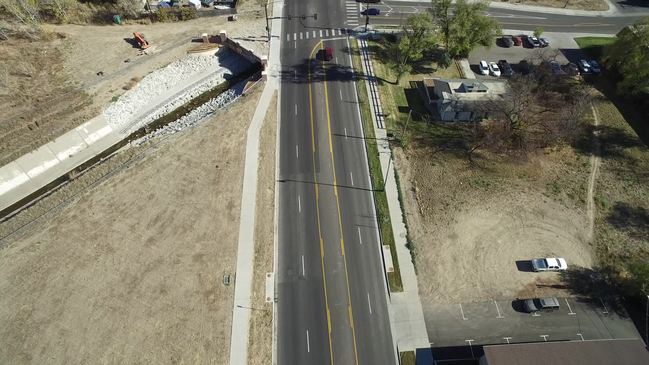 Overhead view of a road beside open dry ground and a rock-lined channel.
