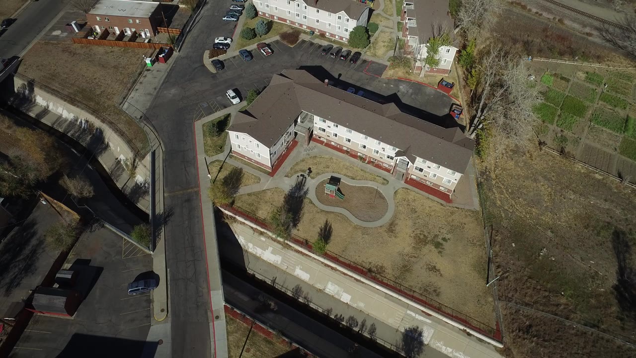 Aerial view of apartment buildings, roads, parking, and dry grass.