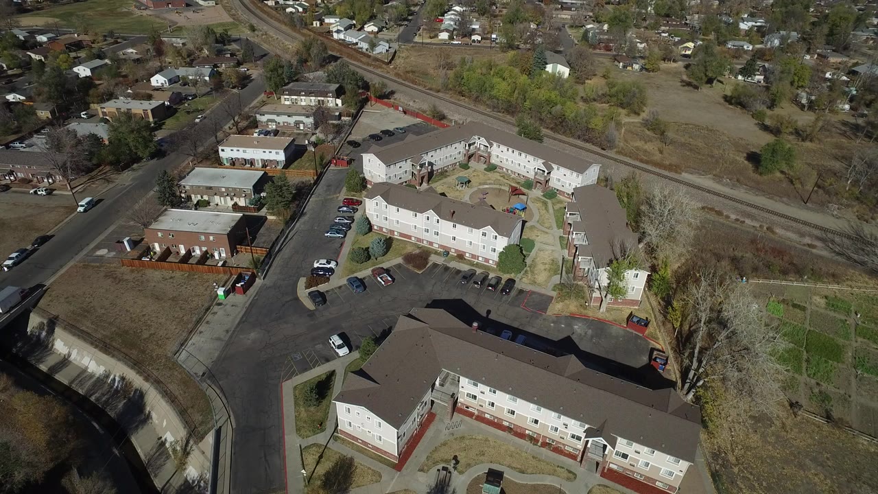 Aerial view of apartment buildings, parking lots, roads, and nearby homes.