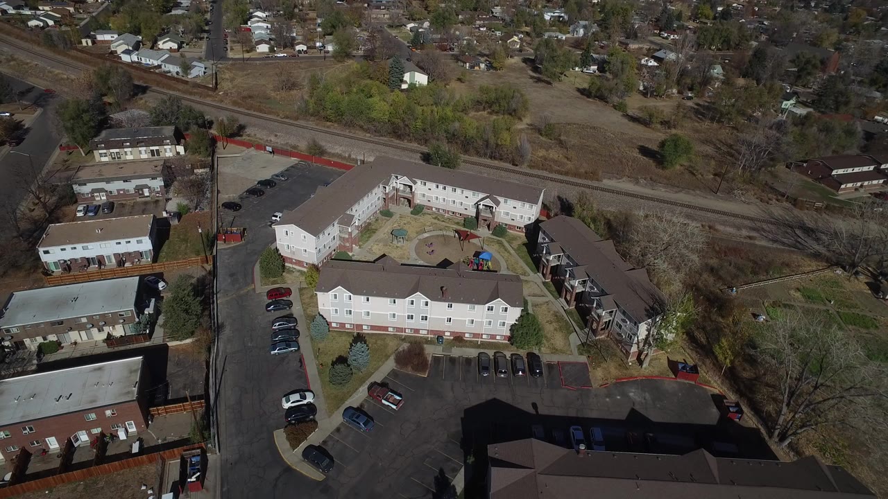 Aerial view of apartment buildings, parking lots, roads, and nearby houses.