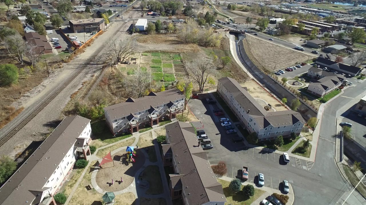 Drone view of apartments, parking lots, streets, tracks, and surrounding neighborhood.