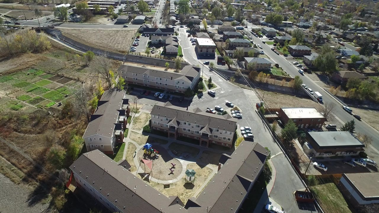 High aerial view of townhomes, streets, parked cars, trees, and a playground courtyard.