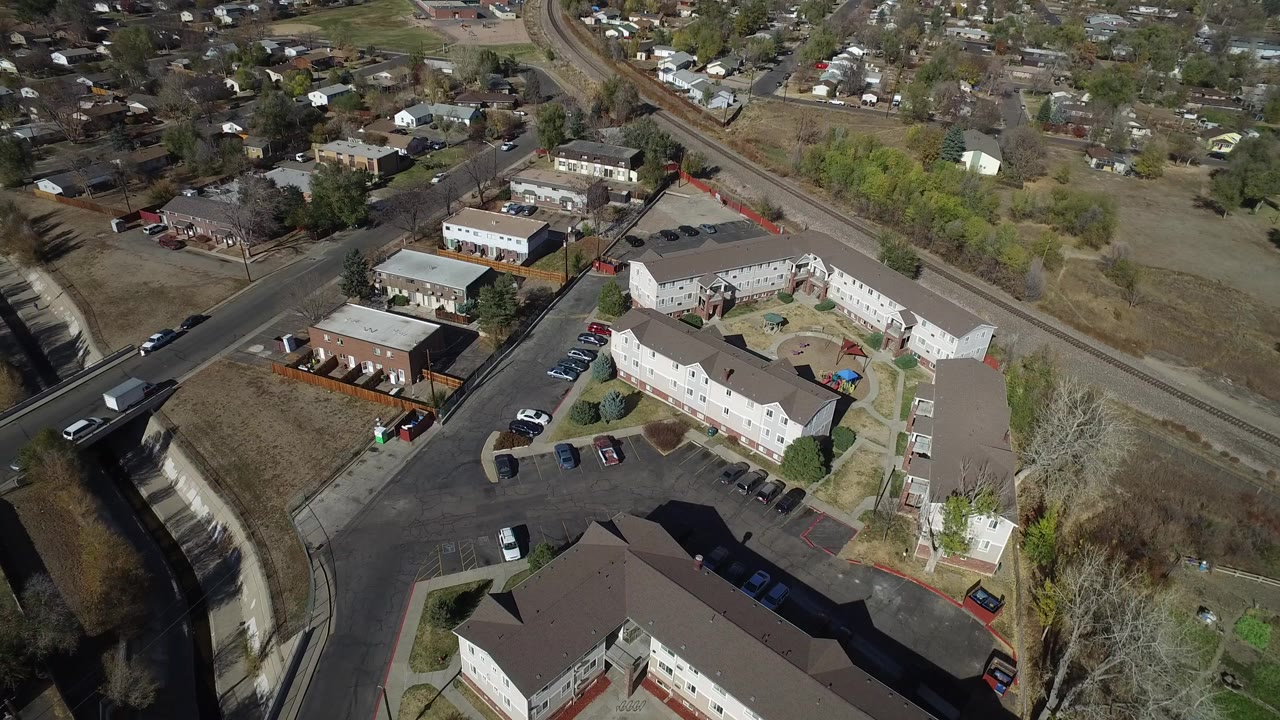 Aerial view of apartment buildings beside a curving road and parked cars.