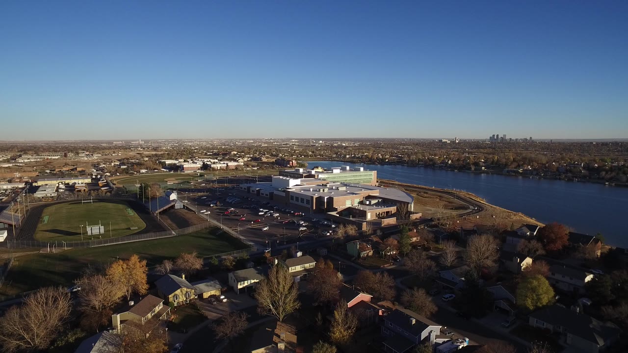 Aerial view of suburban homes, sports fields, large buildings, and a lake