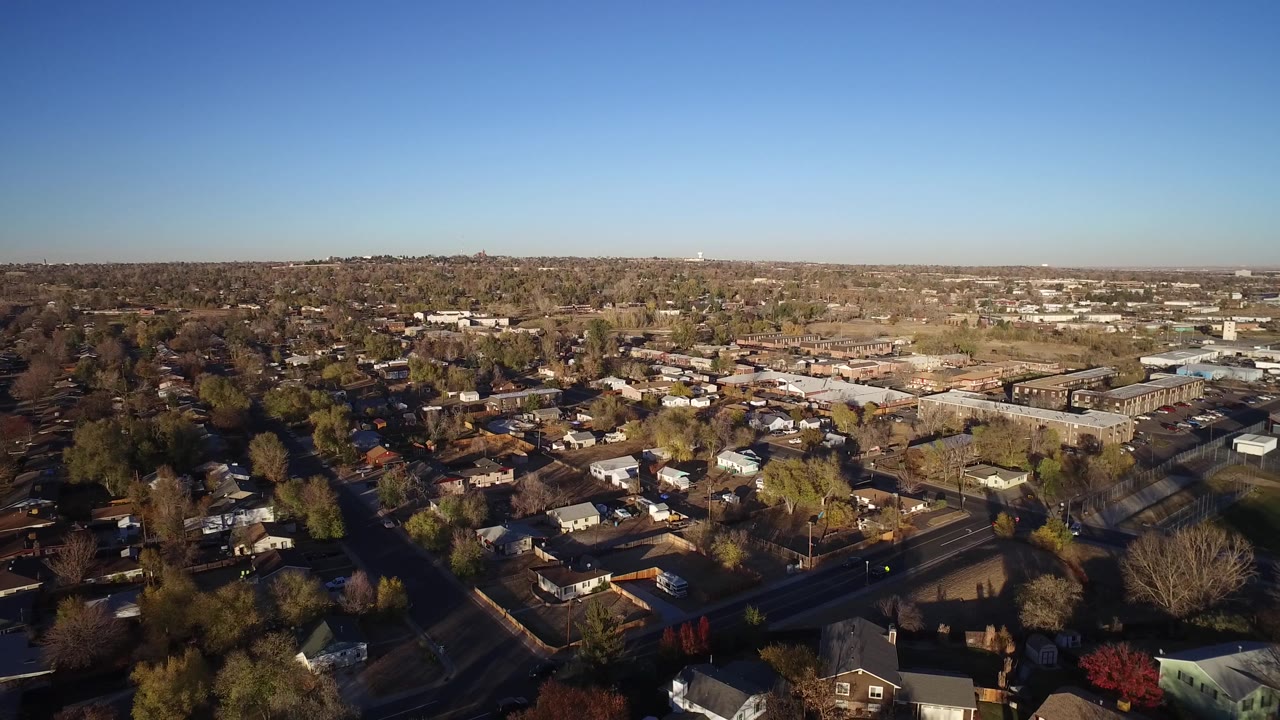 Aerial frame over Westminster, Colorado showing rooftops, bare trees, intersecting streets, low buildings, and no visible people.