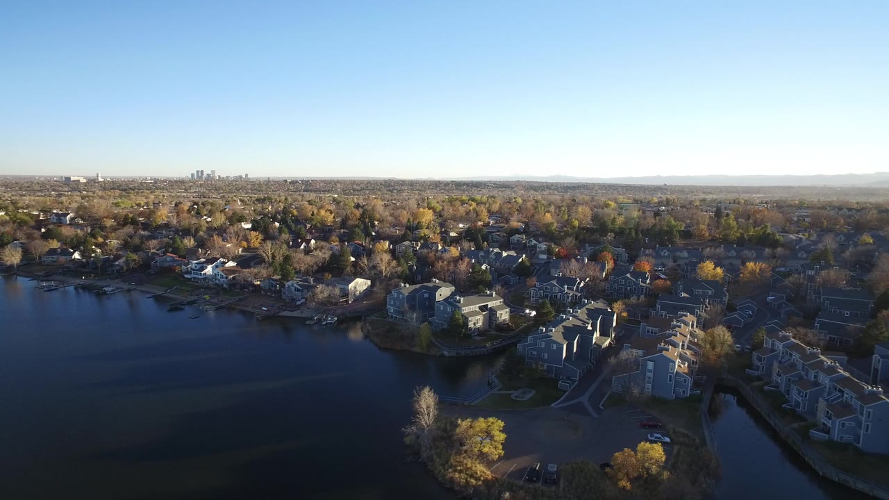 Aerial view of homes around a dark body of water under blue sky.