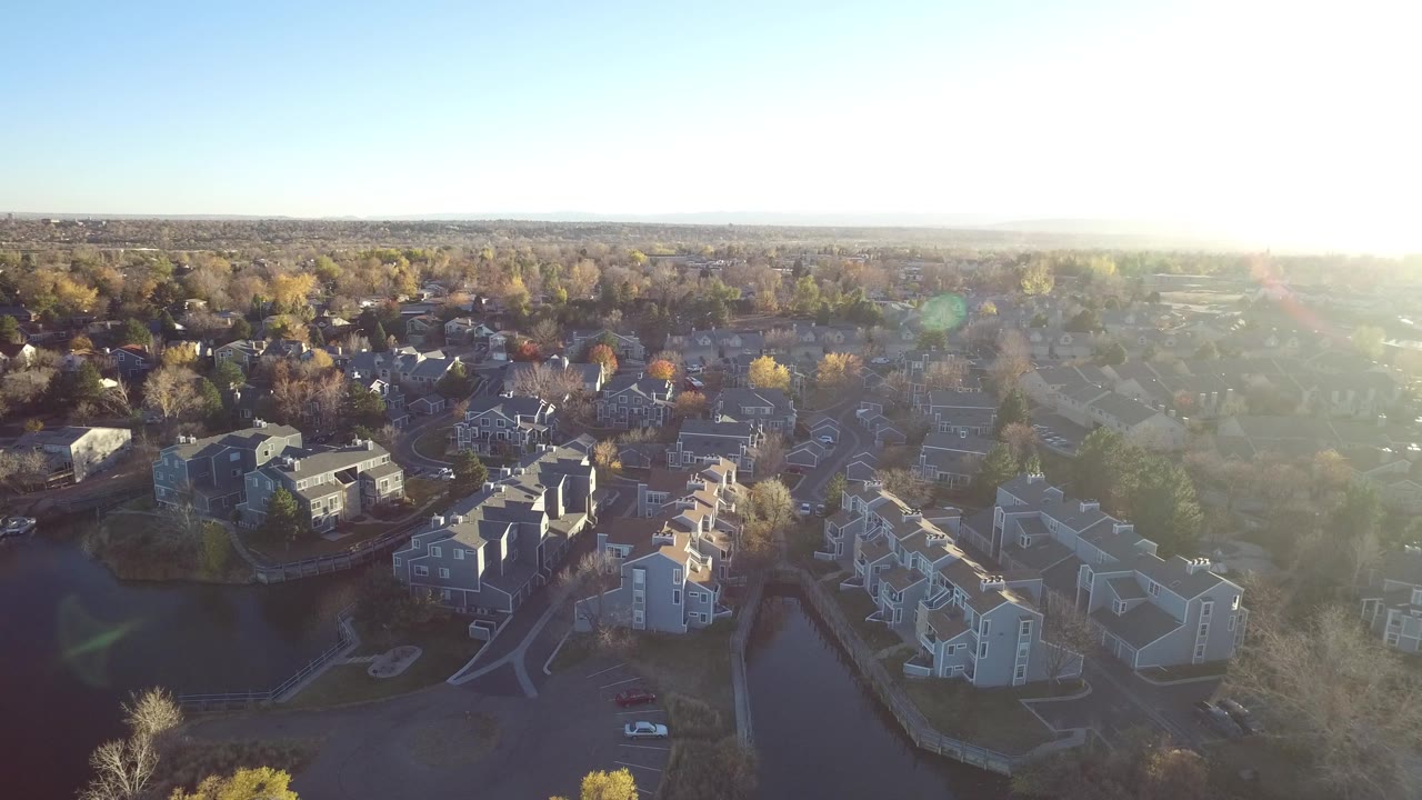 Aerial apartment complex with bright morning flare over suburbs.