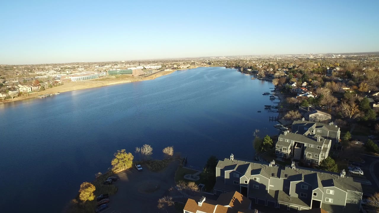 Aerial view over a blue lake with homes in the foreground and shoreline buildings beyond.