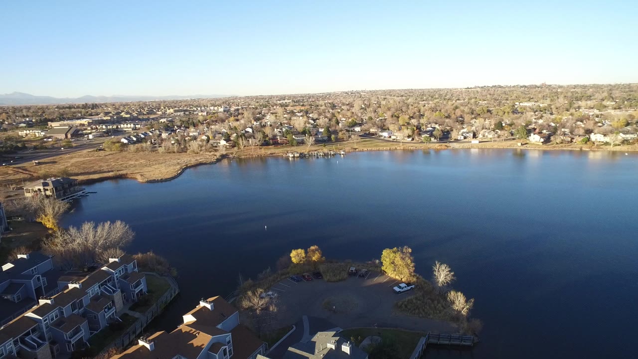 Aerial view of a pond bordered by residential buildings and trees.