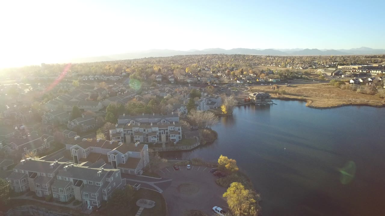 Aerial view of condominiums beside a lake under bright sun glare.