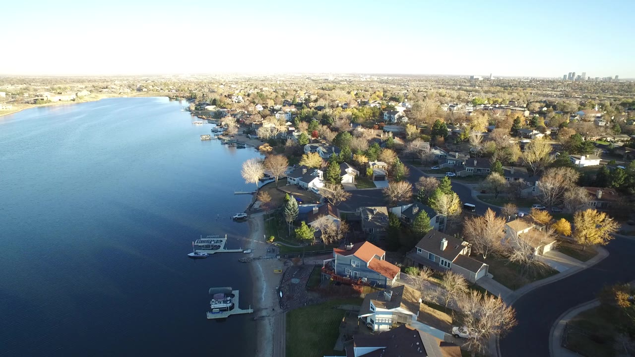 Aerial view of lakefront homes, docks, and autumn trees beside a broad lake.