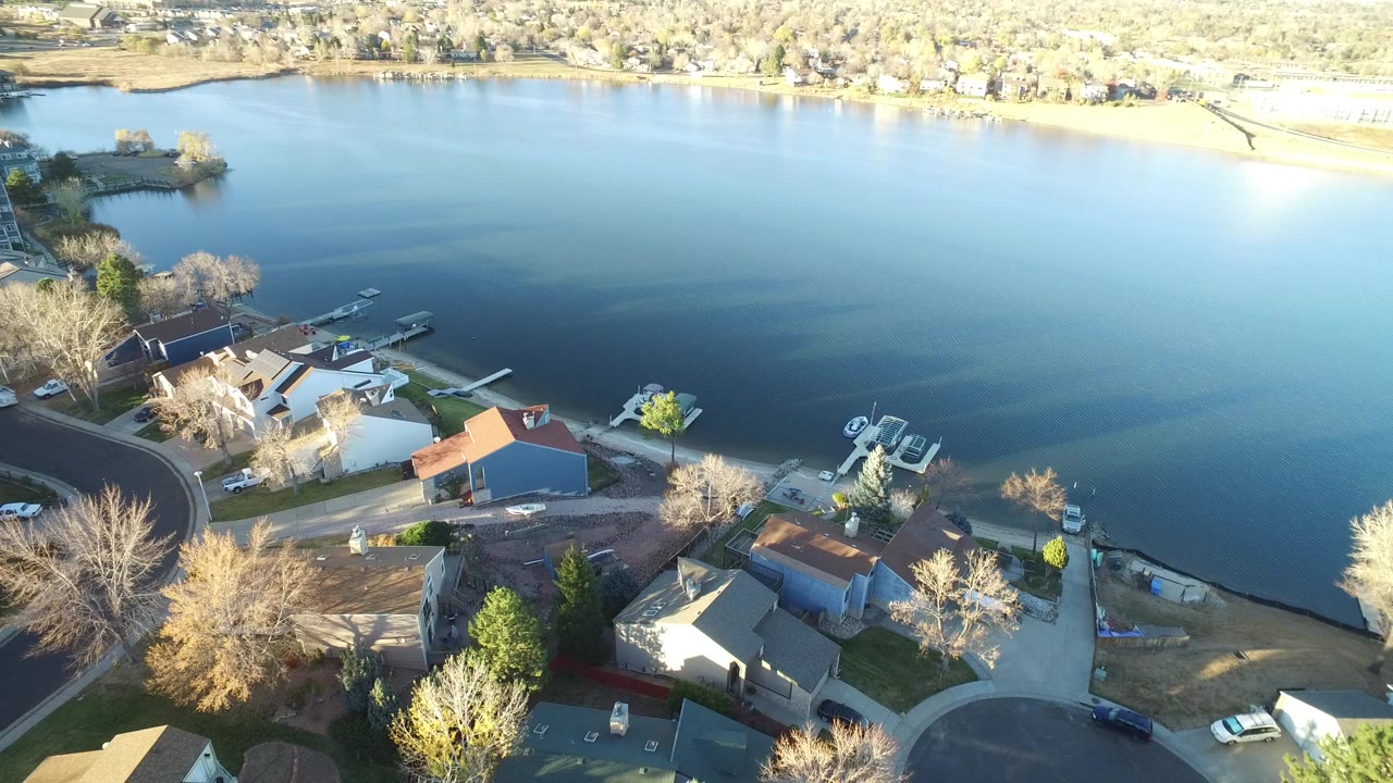 Aerial view of lakeside homes, docks, boats, and calm water.