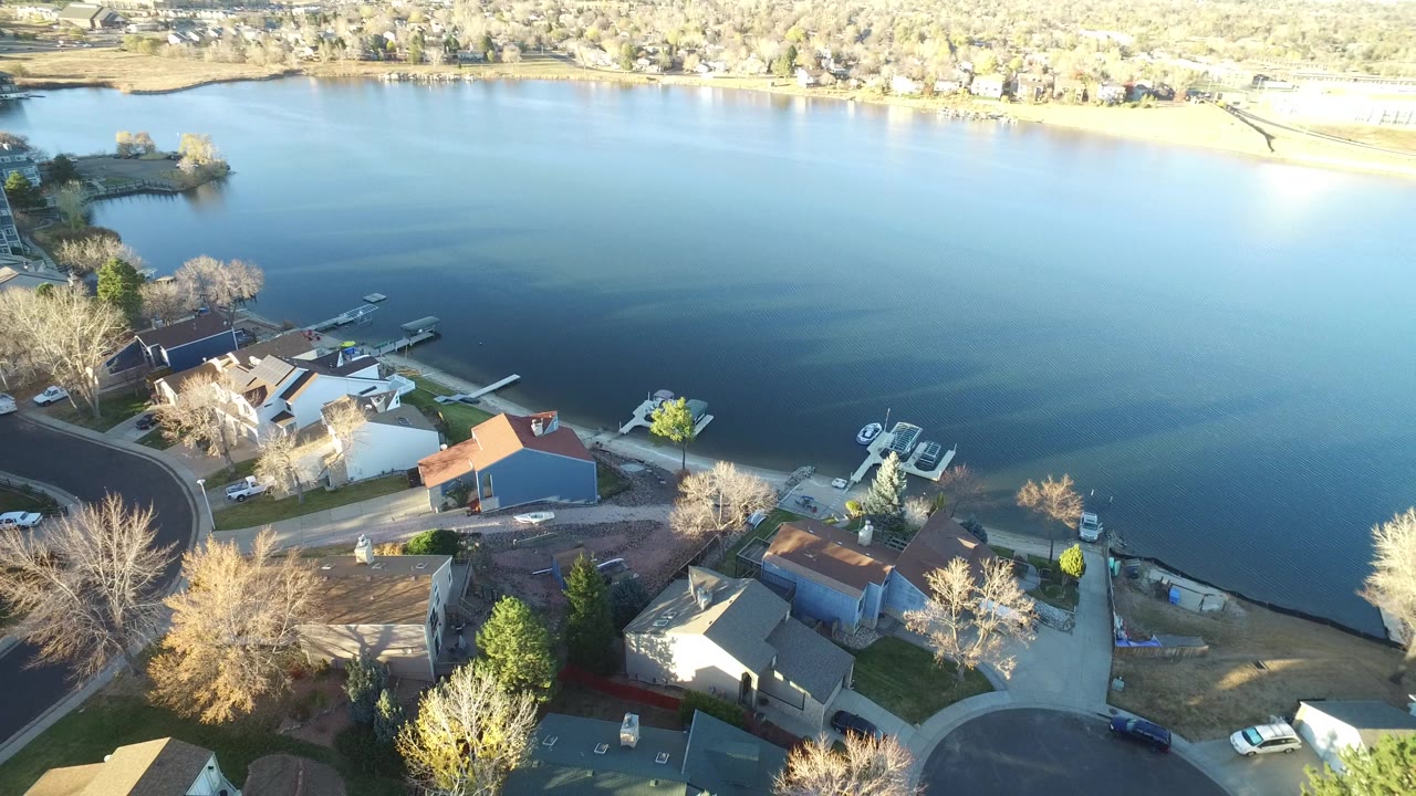 The second frame keeps the Westminster lakeside homes in the lower foreground while more open blue water fills the center, with docks, boats, driveways, trees, and no visible people.